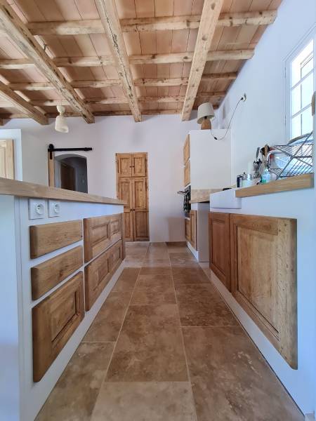 Création d’une cuisine traditionnelle rustique avec plan de travail en béton ciré, façades en chêne vieillies et structure peinte à Genève