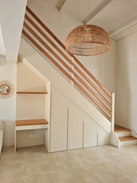 Agencement sous escalier sur mesure avec petit bureau intégré dans style bohème chic avec un mélange laque et chêne à Lausanne