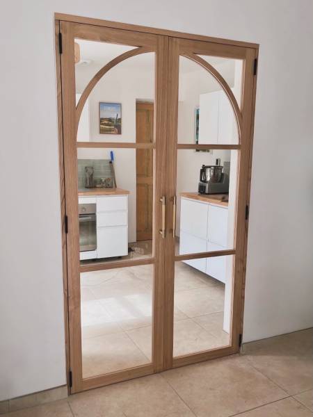 Porte verrière deux vantaux cintrés en châtaignier massif avec verre feuilleté et finition vernis mat, réalisée sur mesure par Le Maillet Bleu à Genève