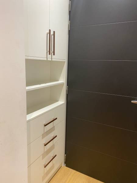 Meuble d'entrée sur mesure en mélaminé blanc avec poignées en noyer massif conçu par Le Maillet Bleu à Genève, optimisant un recoin inutilisé